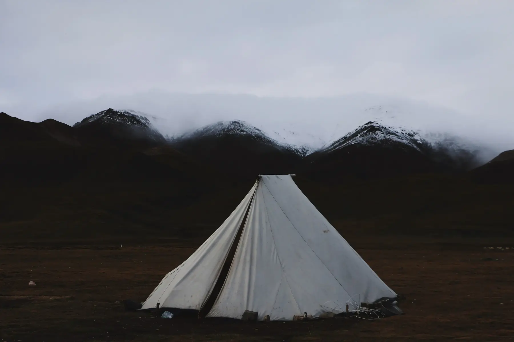 A canvas bell tent under snowy mountains at dusk